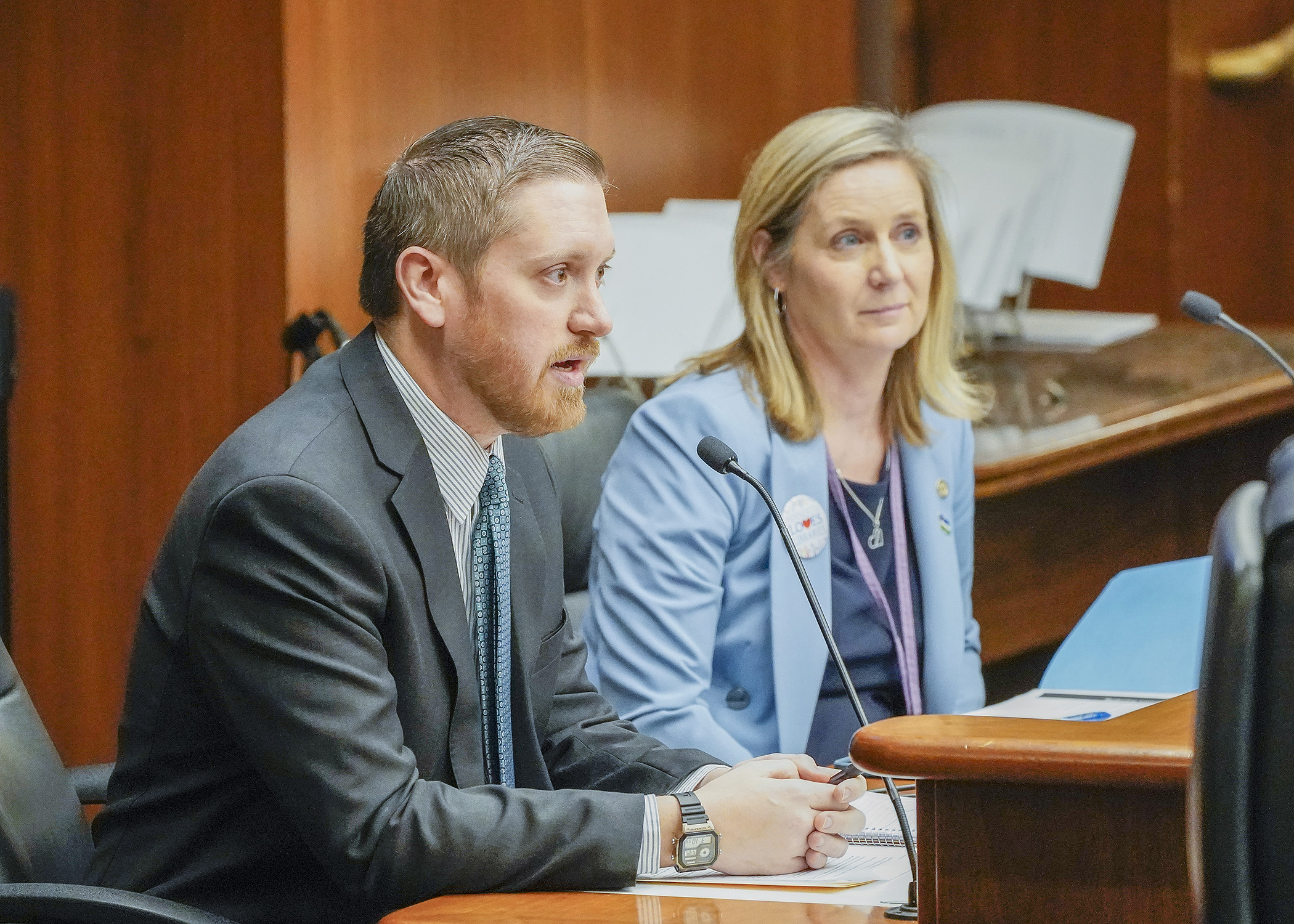 Jon Kelly, director of government affairs with the Department of Commerce, testifies before the House Climate and Energy Finance and Policy Committee Feb. 28 in support of a bill sponsored by Rep. Lucy Rehm, right. (Photo by Andrew VonBank)